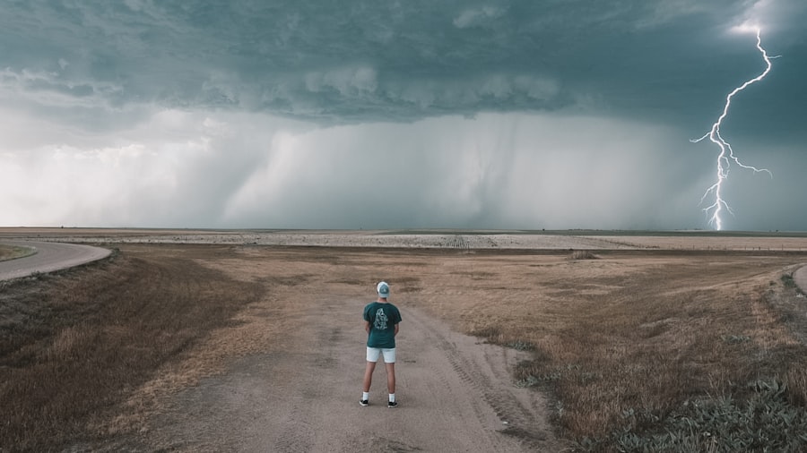 Una persona de pie ante una tormenta con un rayo en el horizonte