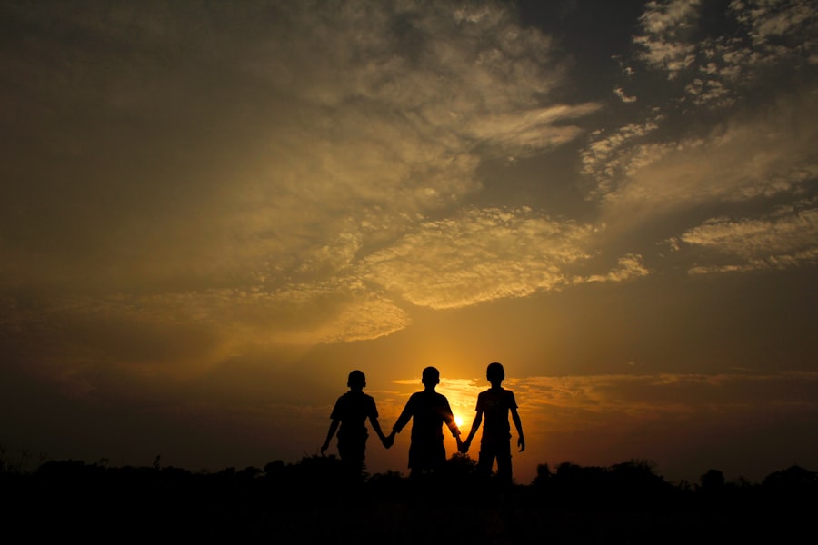Tres personas cogidas de la mano frente a una puesta de sol